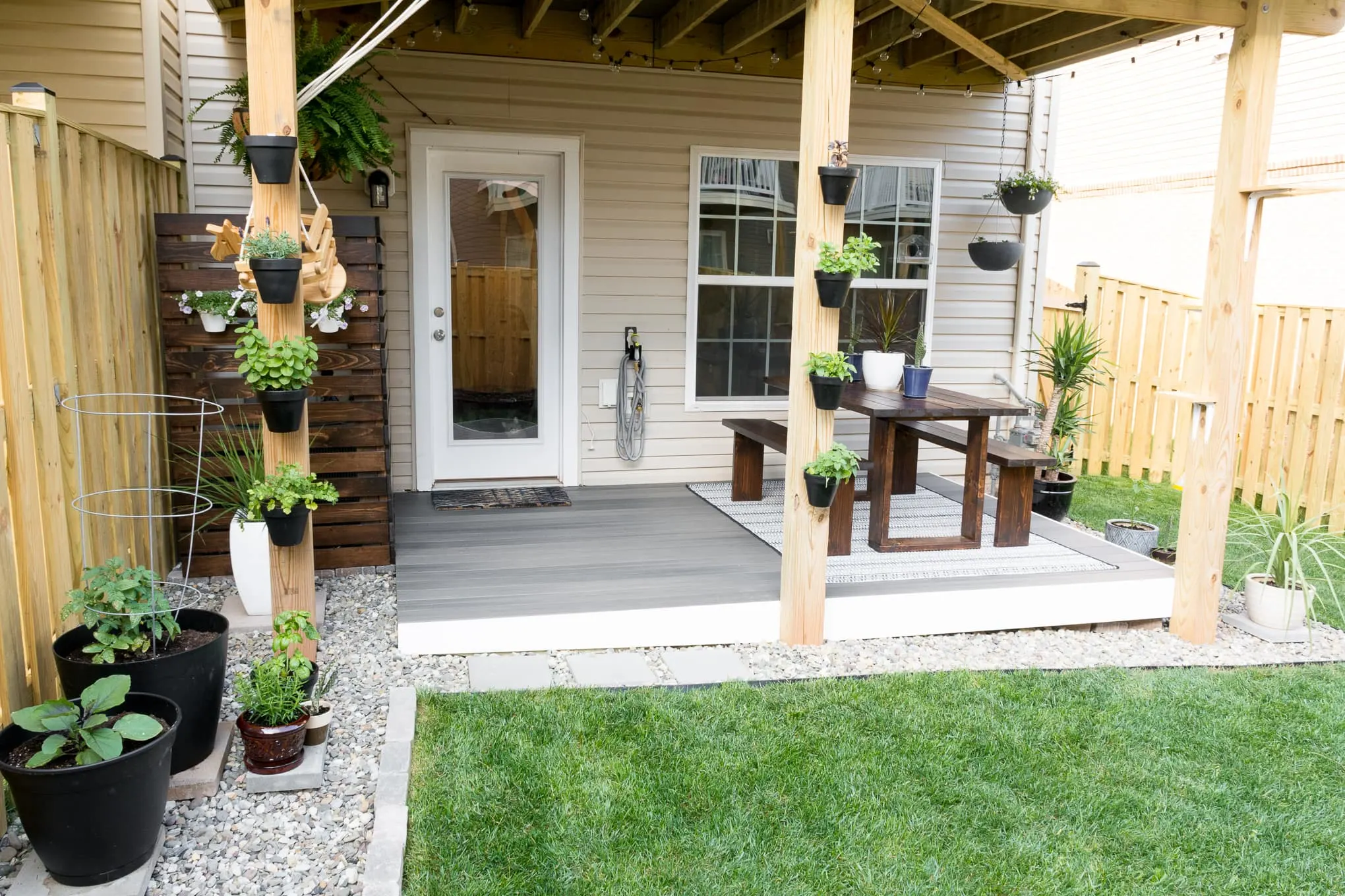 small townhouse backyard with a platform deck, plants, and a table
