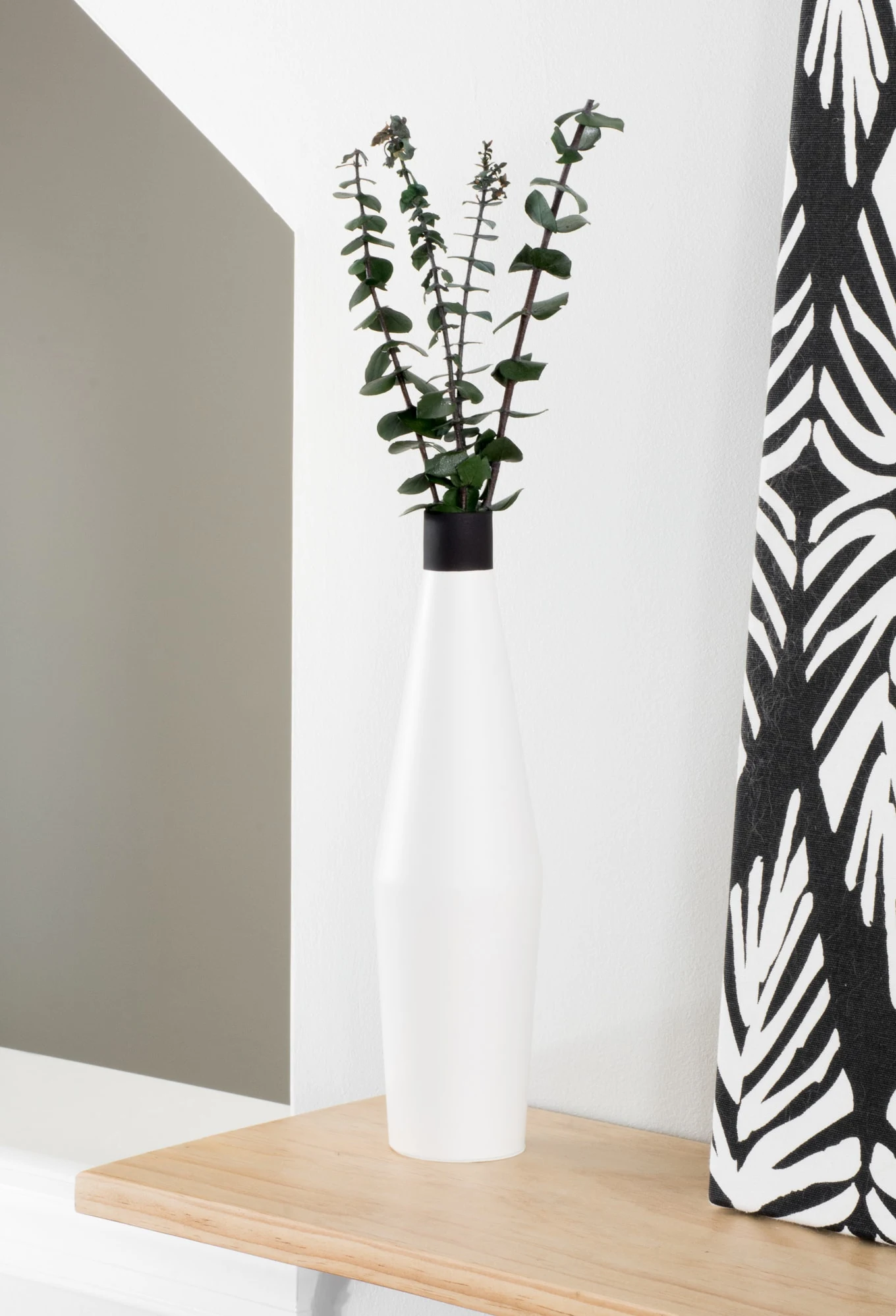 white vase with eucalyptus in it