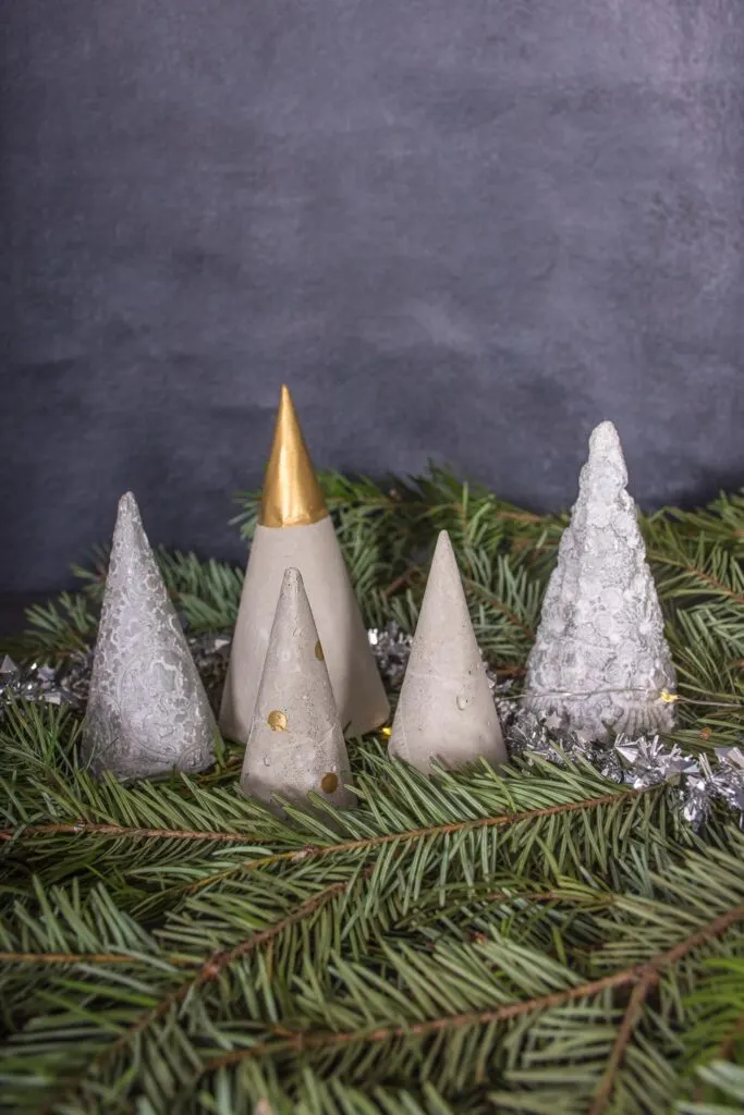 5 Concrete mini Christmas trees sitting on pine greenery
