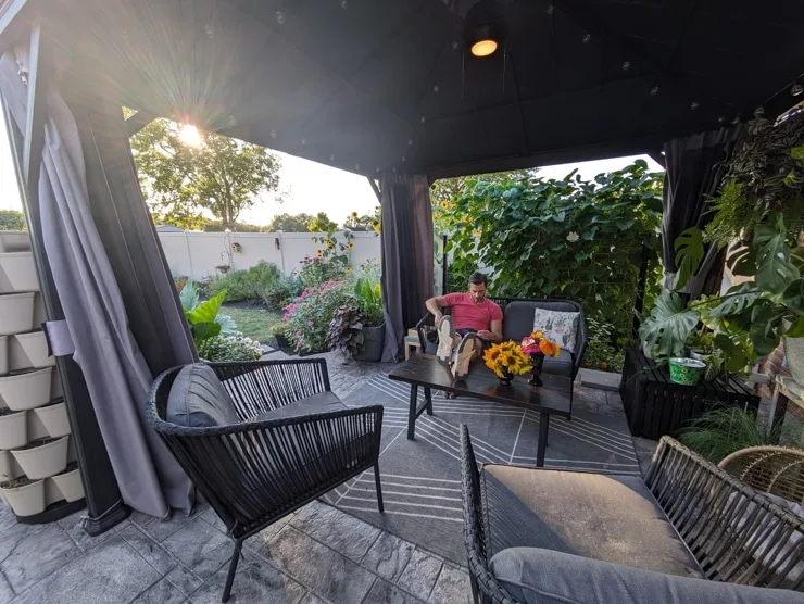man sitting in a gazebo with modern furniture and a ceiling fan